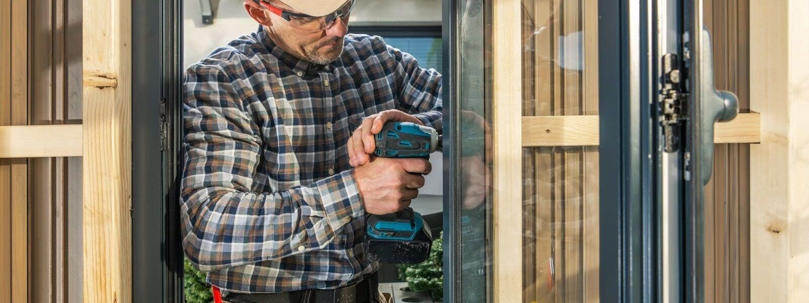 A contractor works on a window with a power tool